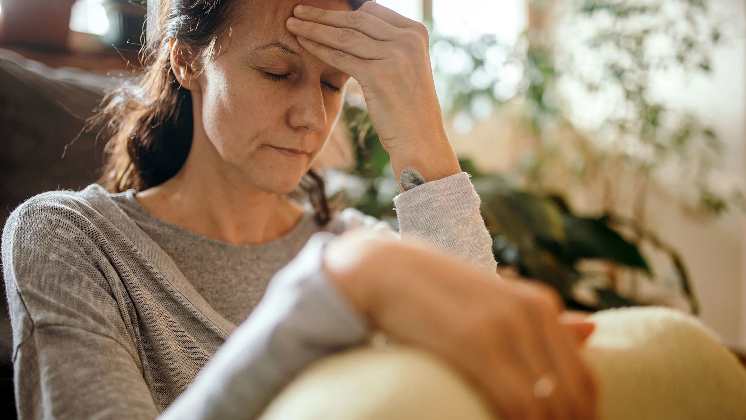 Woman sitting on floor and suffering from a headache