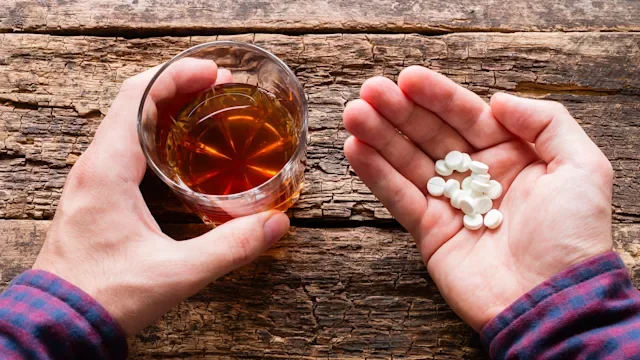 Health: Finasteride: hands holding alcohol and pills-583694202