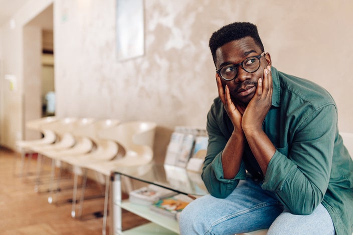 Man sitting in a hospital waiting room looking worried.