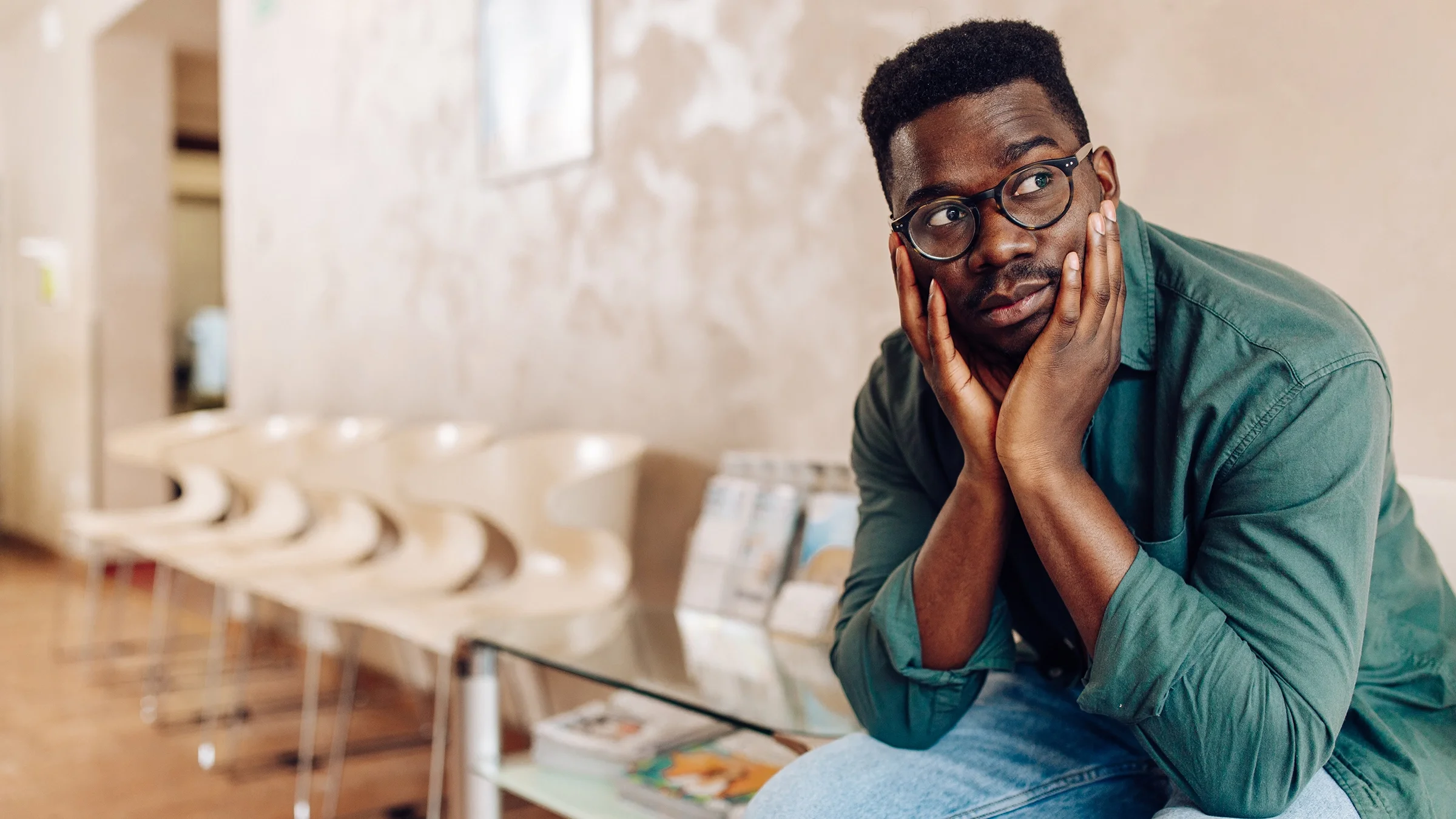 Man sitting in a hospital waiting room looking worried.