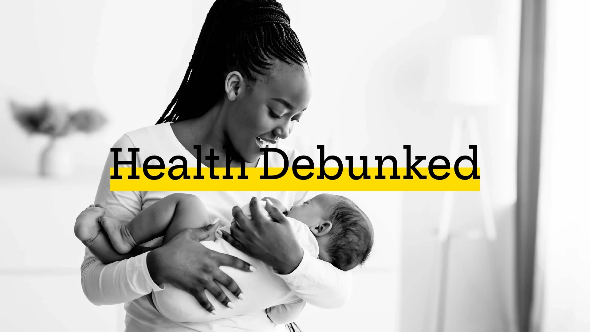Young mom smiling and holding her baby in a brightly sunlit room. There is added text on top reading “Health Debunked” with a yellow highlight bar behind it.