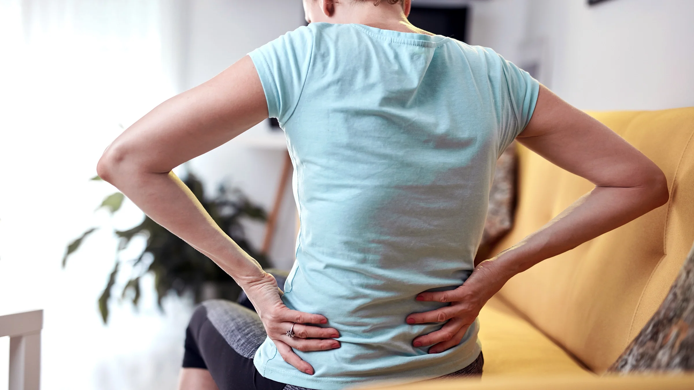 Woman with back and hip pain at home.