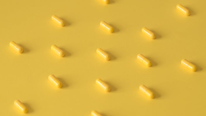 Yellow pills laid out in a pattern on a yellow background.