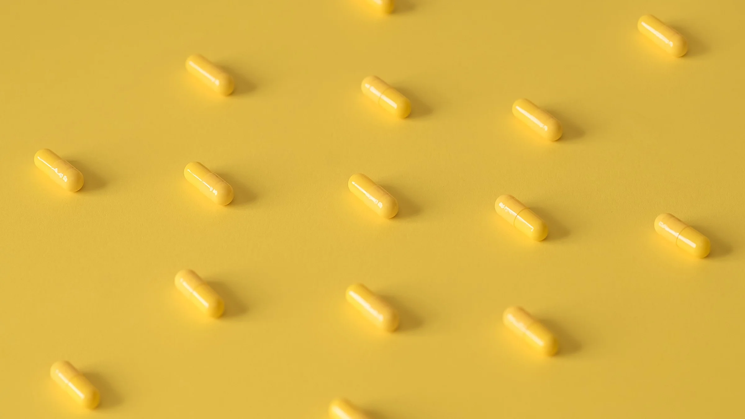 Yellow pills laid out in a pattern on a yellow background.