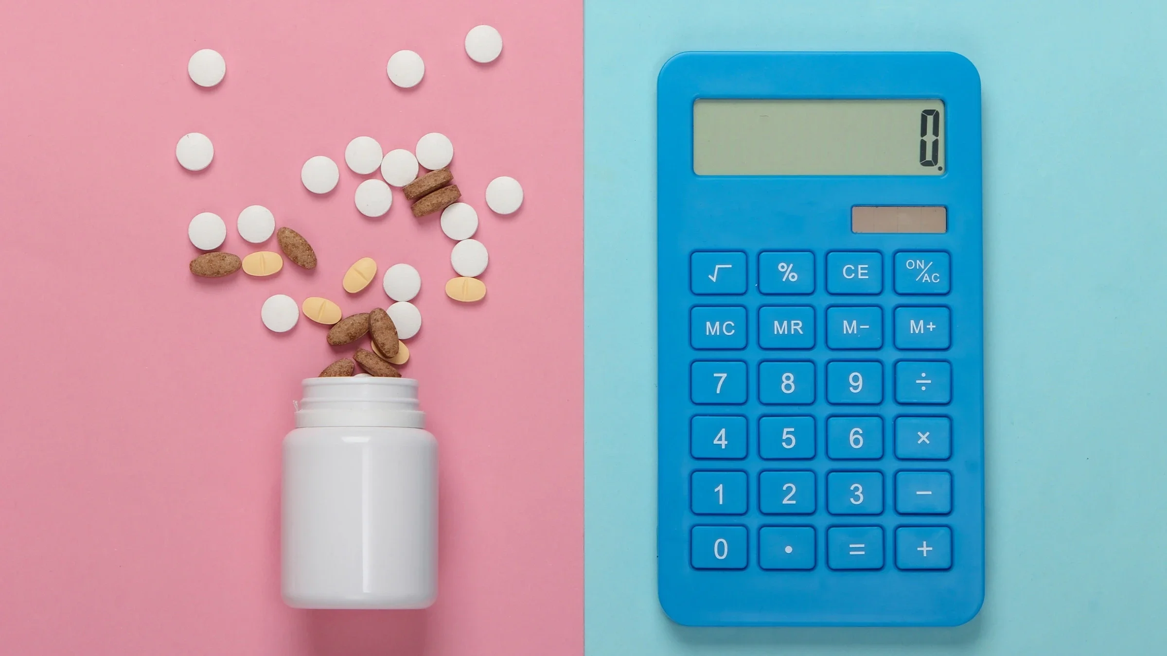 Flat lay image of an open pill bottle with pills coming out on a pink background on one half. The other half is a blue calculator on a light blue background.