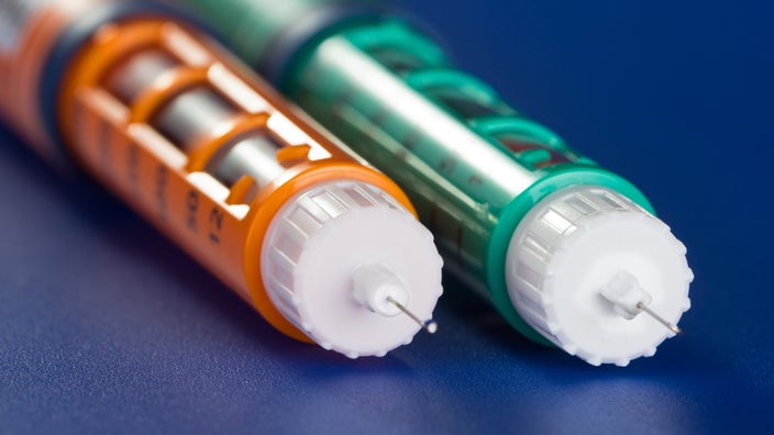 Two insulin pens side by side on a blue background.