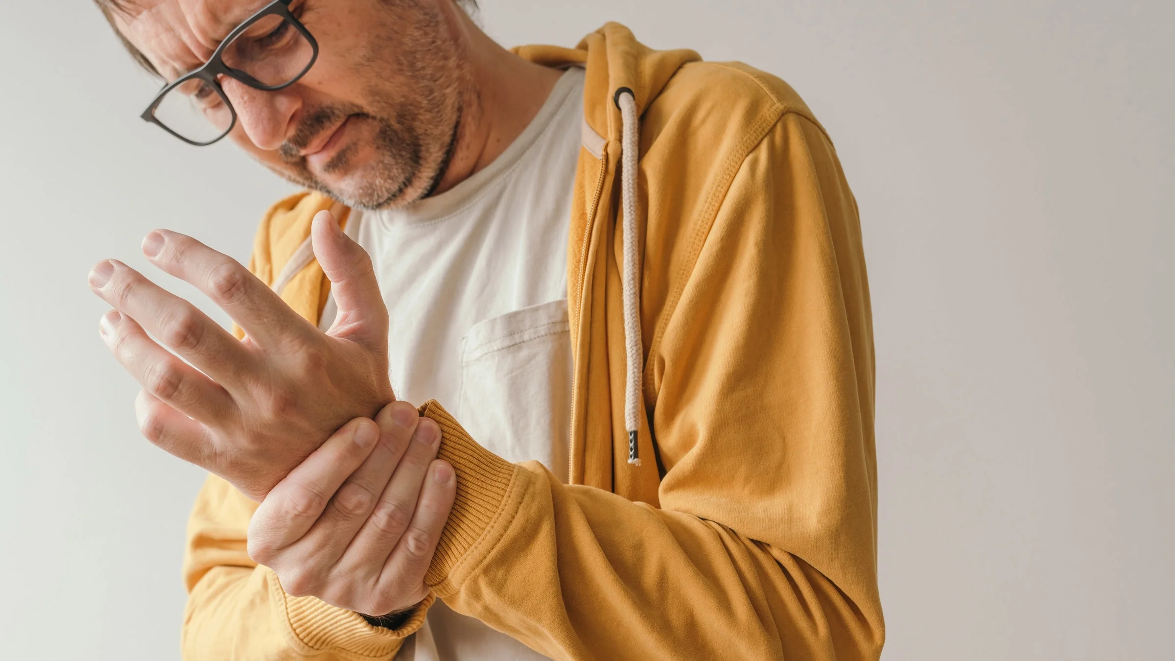 A person holding their wrist in pain and with a stressed out expression.