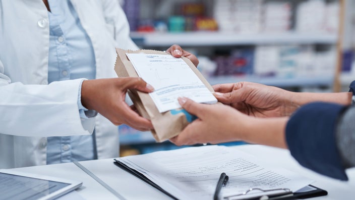 Pharmacist handing patient prescription.