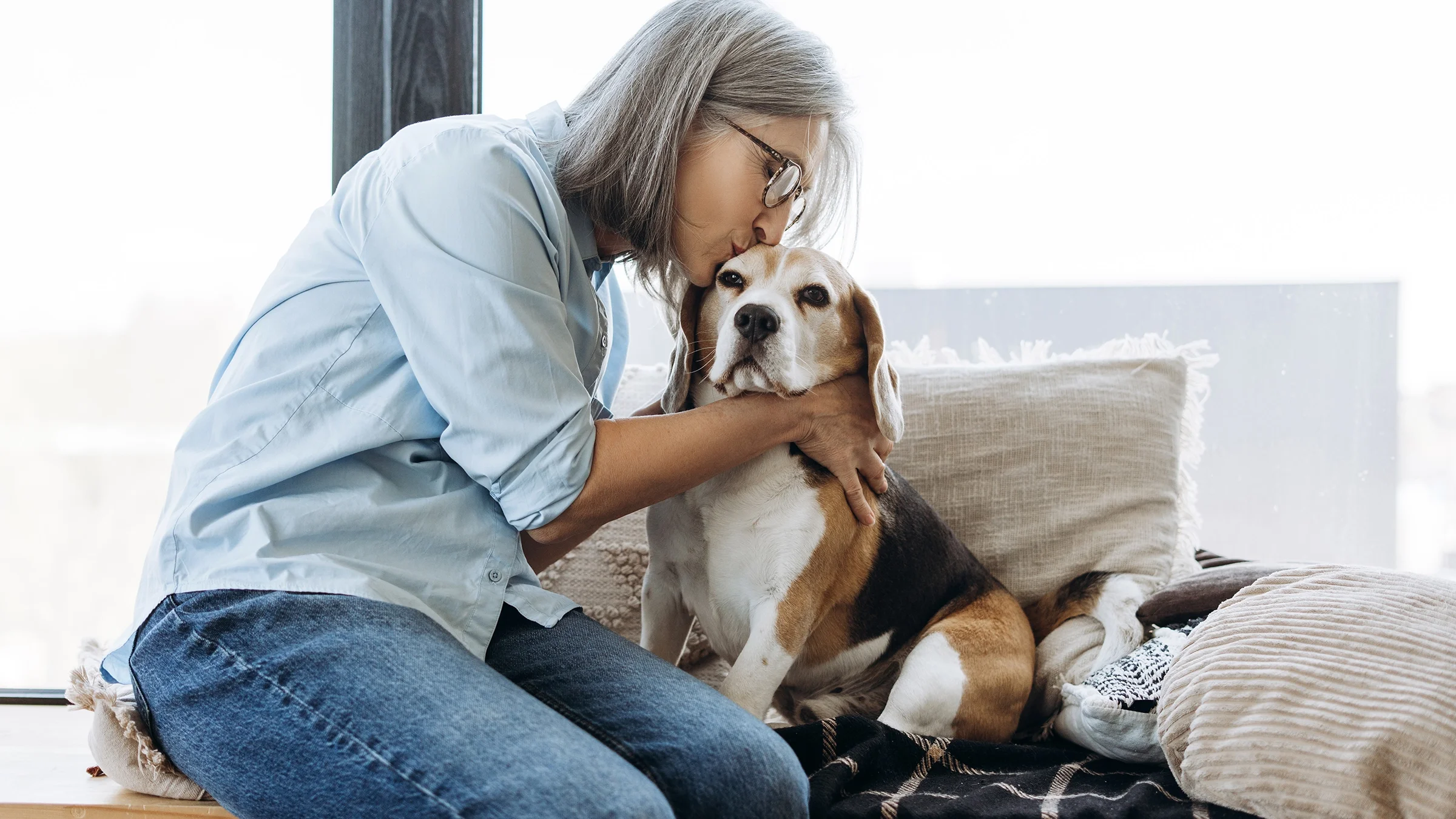 A woman hugs her beagle dog.