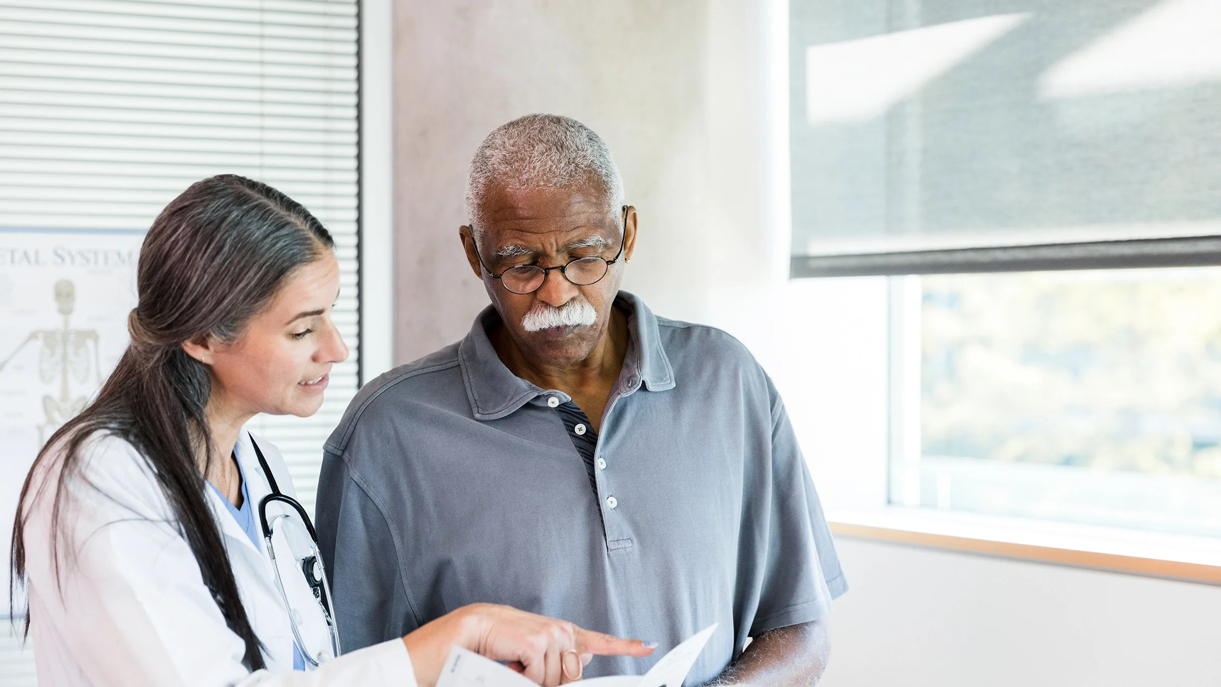 A healthcare professional talks with a man as they look at test results.
