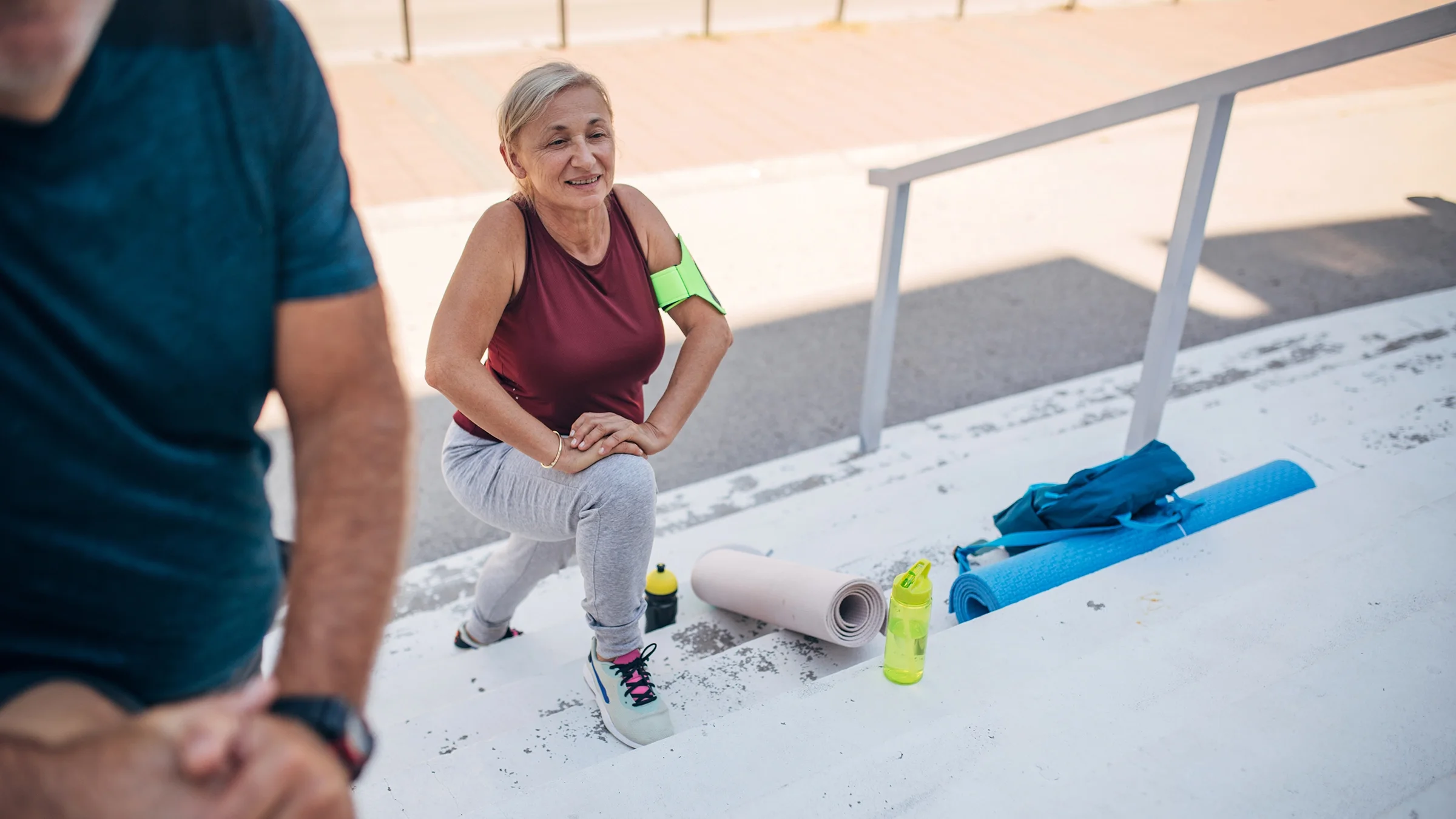 A senior couple exercises together on outdoor stairs.
