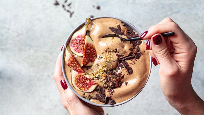 Woman holding a bowl of chocolate smoothie with figs