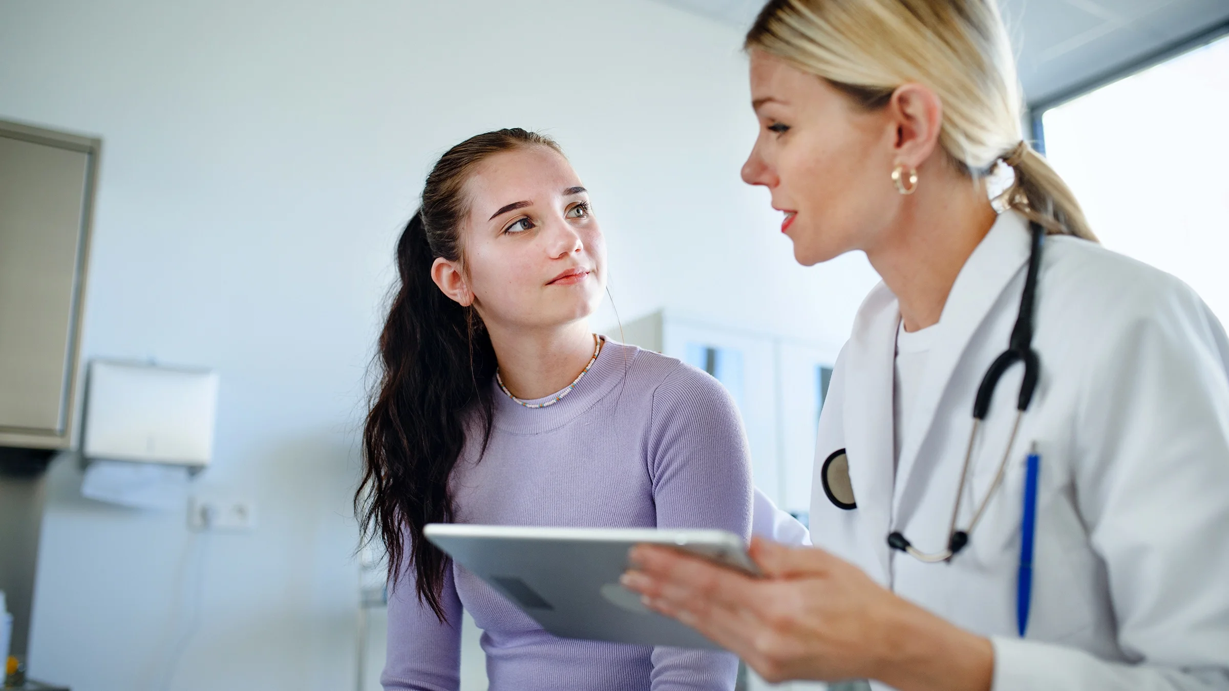 A healthcare professional explains a diagnosis to a teen girl.