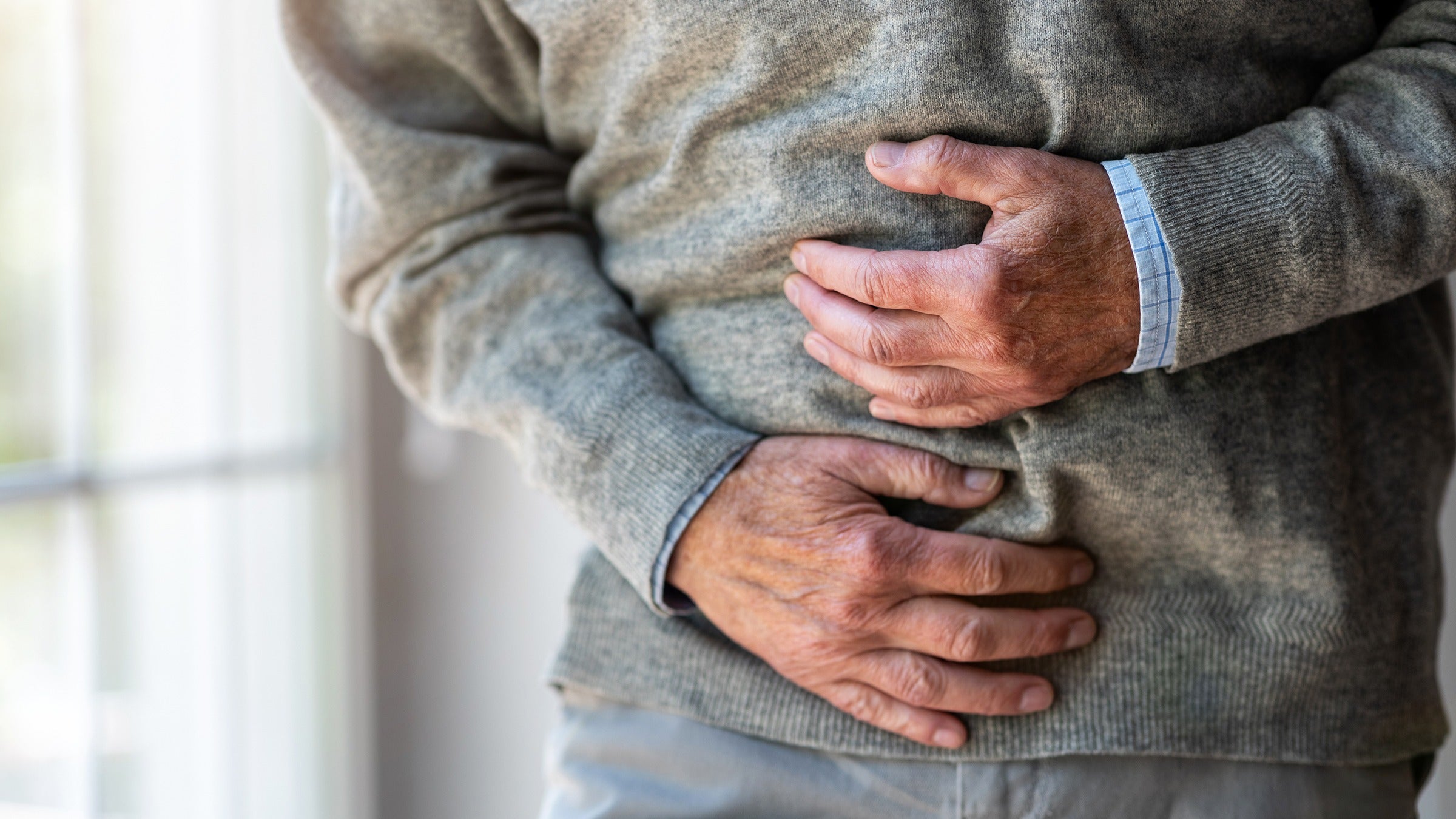 Health: Pain: man clutching stomach in pain-1253815309