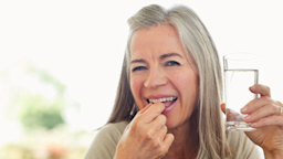 Woman holding glass of water taking pill.
Sam Edwards/ OJO Images via Getty Images