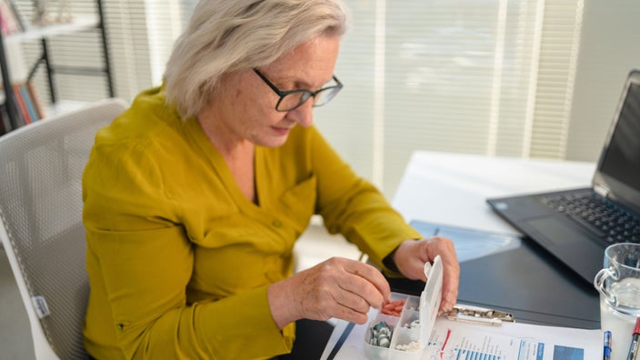 Woman organizes medicine in pill container