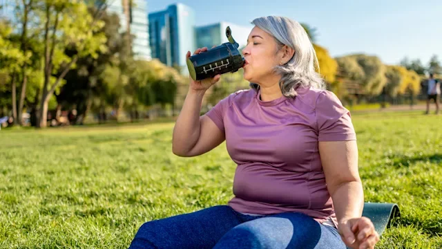 menopause: woman drinking protein shaker cup 1345759538