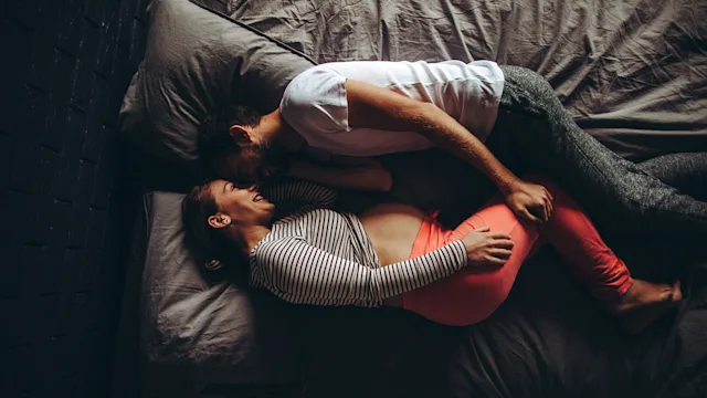 Pregnancy: pregnant woman and man lying in bed 870773732