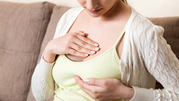 A cropped shot of someone examining their breast.