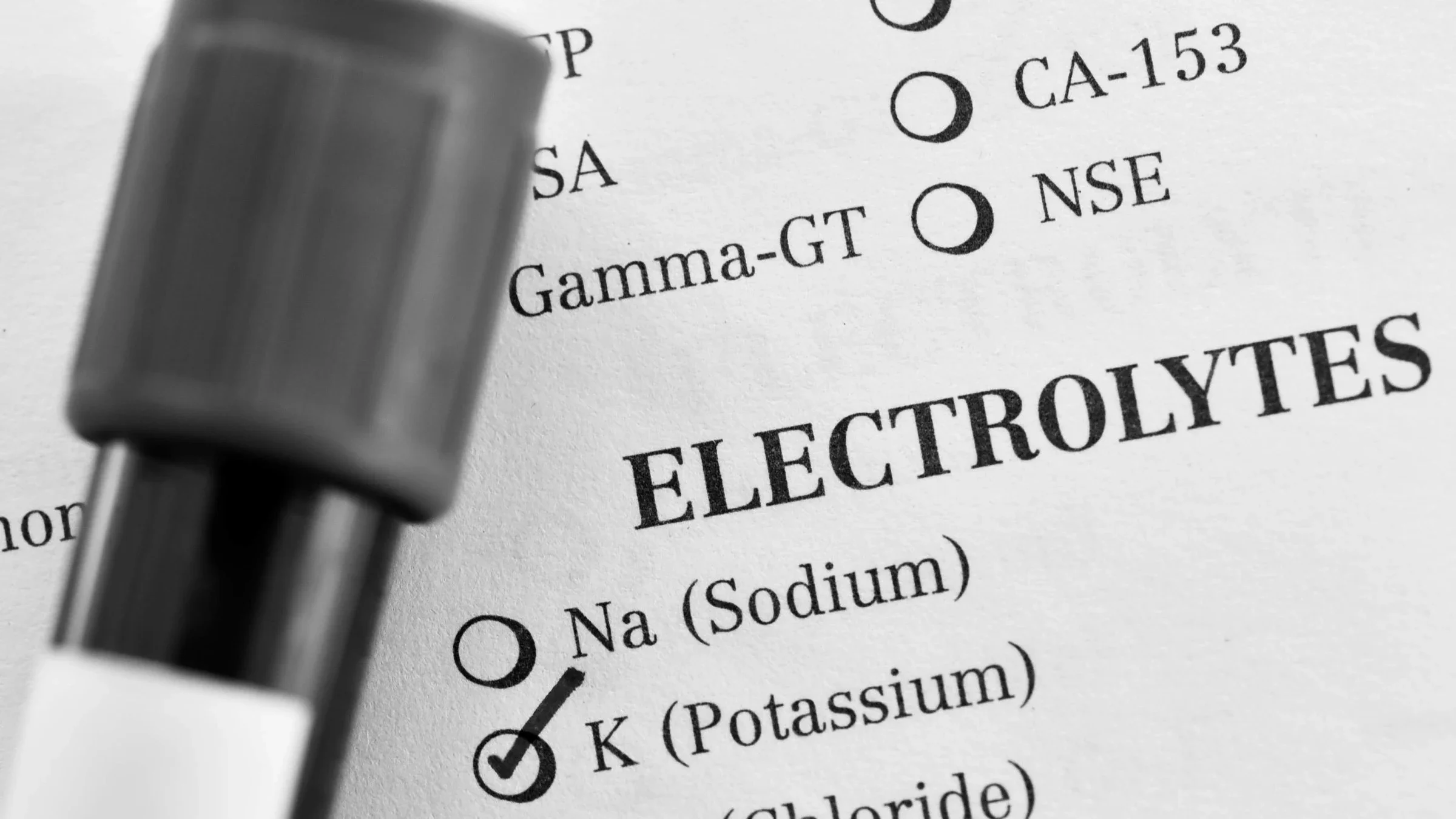 Black and white close-up of a blood vile on top of a lab test request for potassium.
jarun011/iStock via Getty Images