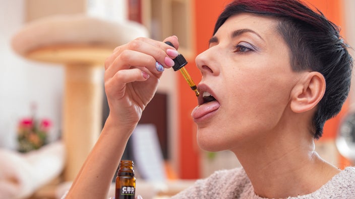 Dropping CBD oil on tongue.