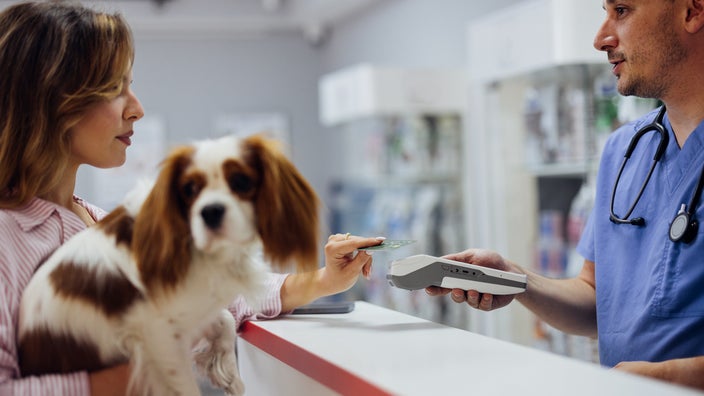 A woman pays for her dog’s visit to the veterinarian.