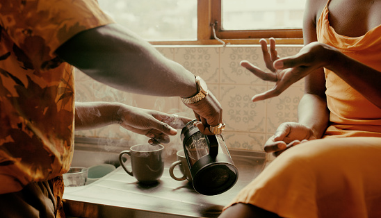 Close-up on a person serving coffee to their partner next to them on the kitchen counter.