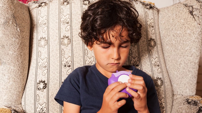 A boy uses an asthma inhaler.