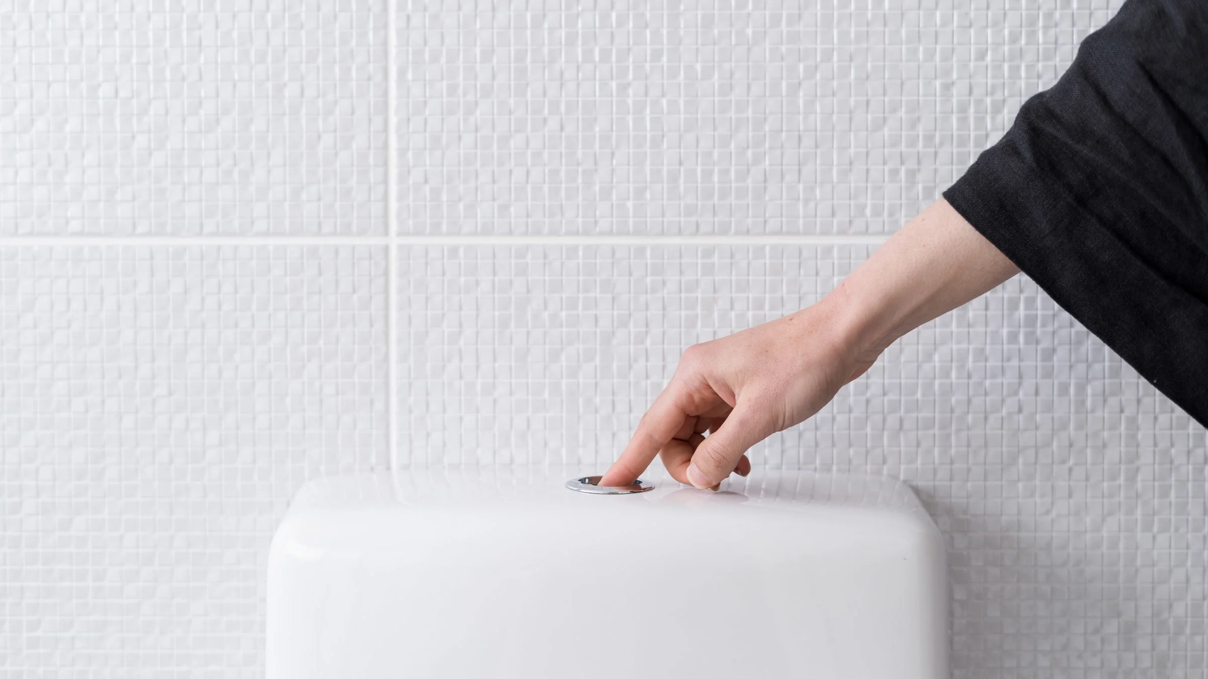 A hand flushing a toilet.