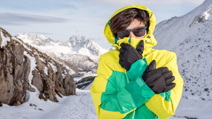 A woman is hiking in extreme weather on top of a snowy mountain.