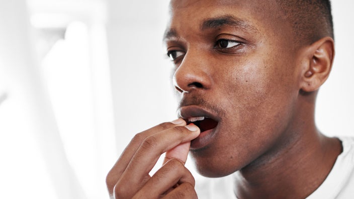 Close up of a man taking a pill.