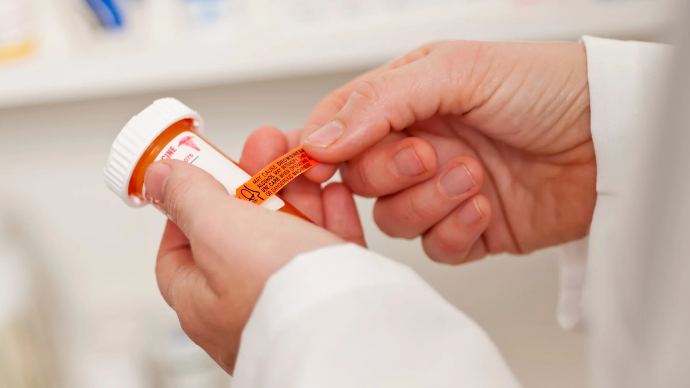 Cropped shot of a pharmacist applying a warning sticker to a pill bottle.