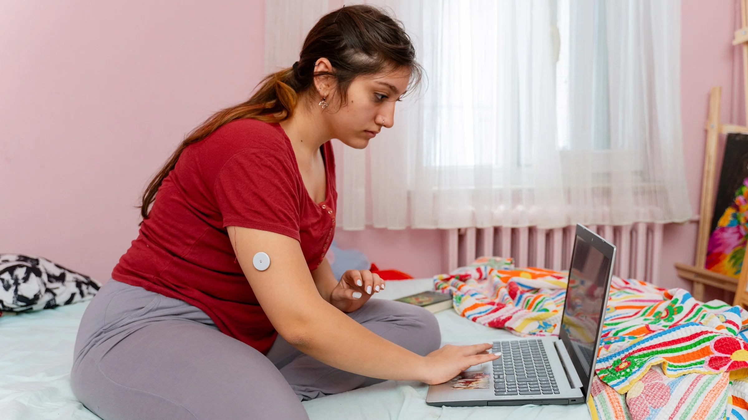 A person who wearing a glucose monitor looking something up on their laptop.