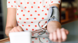 Cropped shot of a woman in a white and red polk-a-dot t-shirt taking her blood pressure.
javi_indy/iStock via Getty Images
