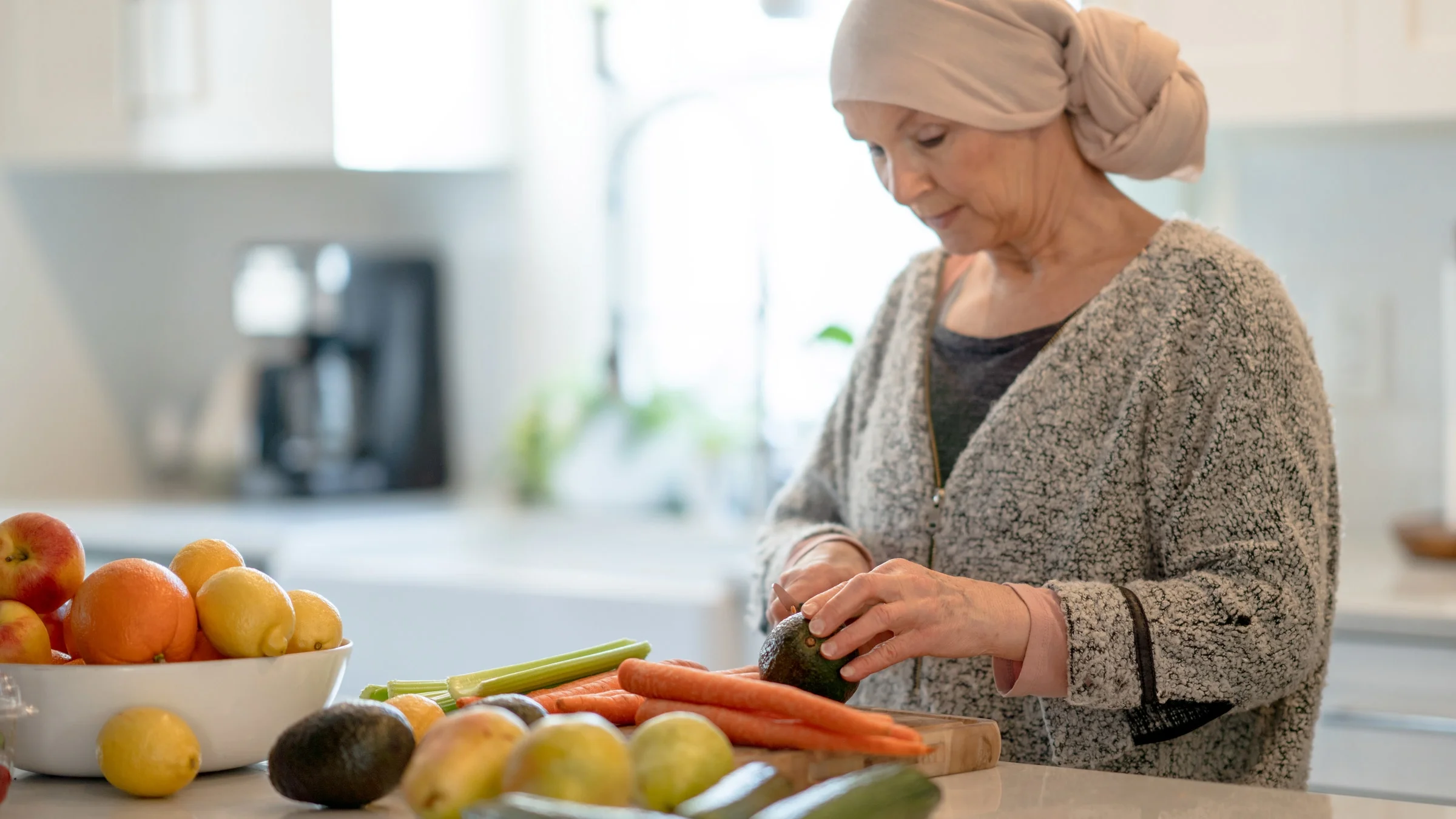 A cancer patient cutting vegetables in their kitchen.