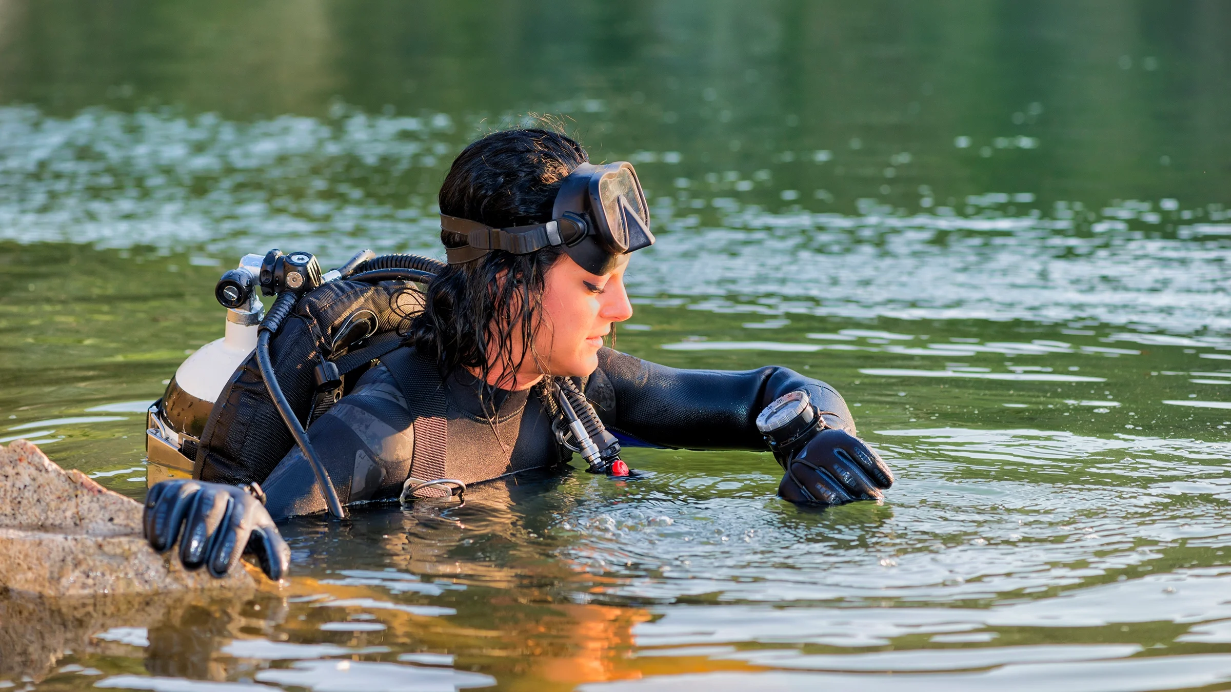 Diver coming up from the water, checking pressure levels on their wrist device.