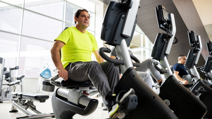 A man is exercising at the gym using a recumbent bike.