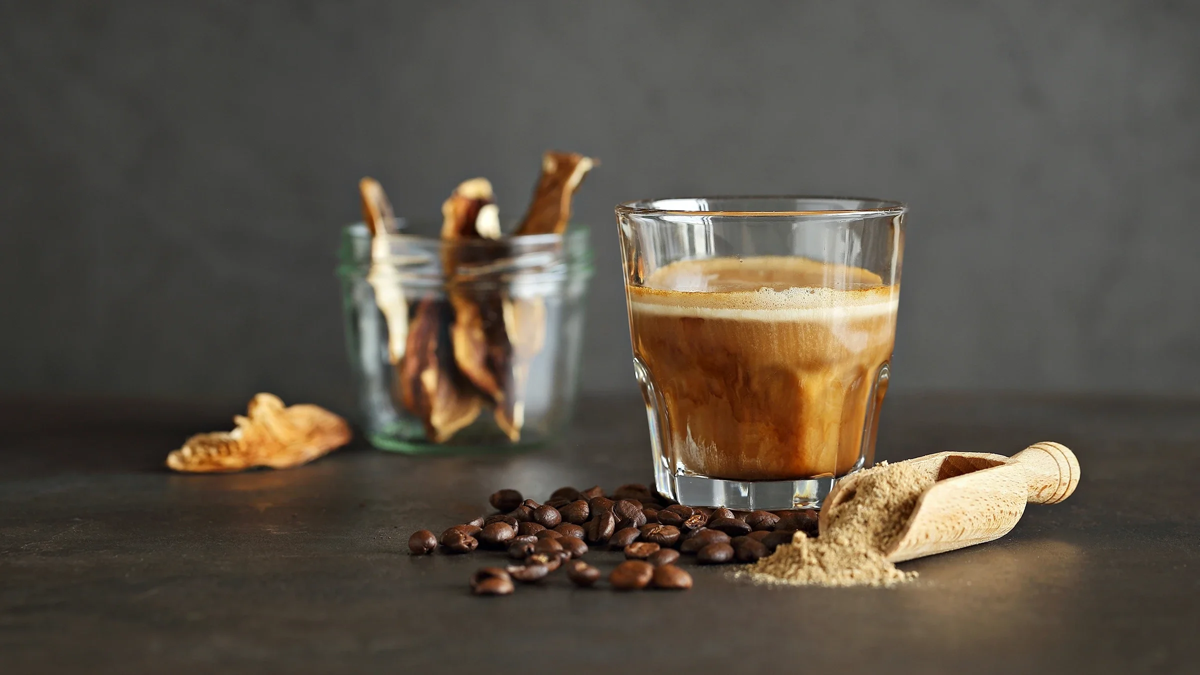 Mushroom coffee in a glass with coffee beans and dry mushrooms