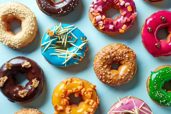 A variety of colorful frosted donuts on a light blue background.