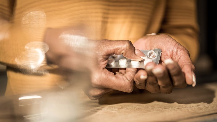  A woman removes a tablet from a blister pack.