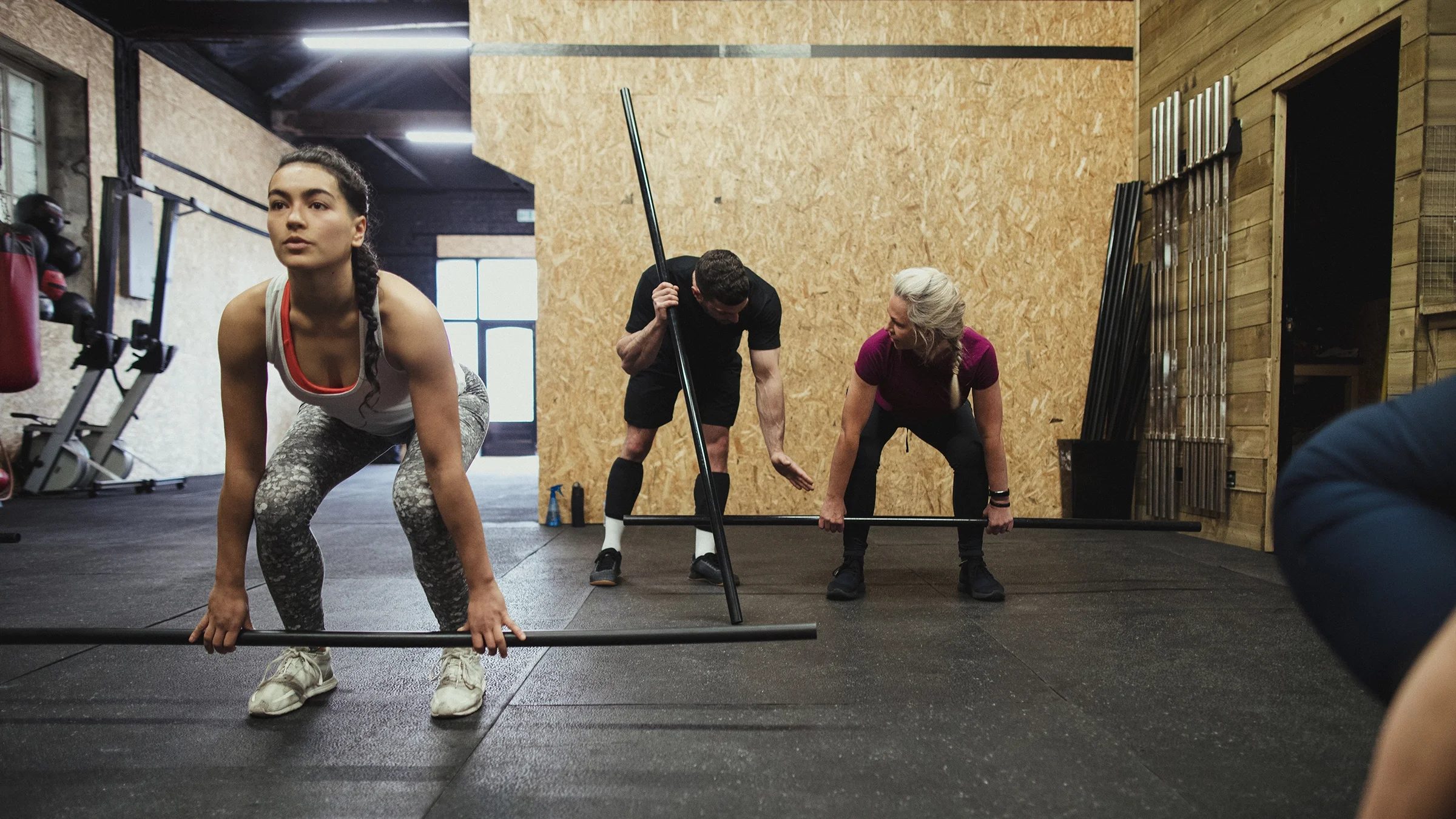 A woman is doing a squat exercise with an exercise bar.