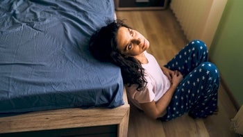Menopause: Mental health: sad middle-aged person by foot of bed 1075048598