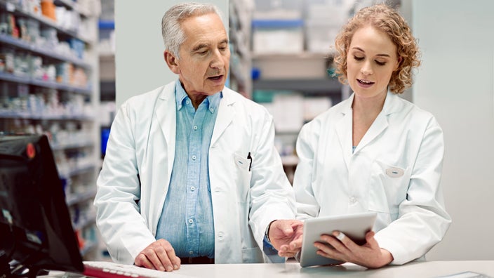 Two pharmacists using a laptop and tablet.