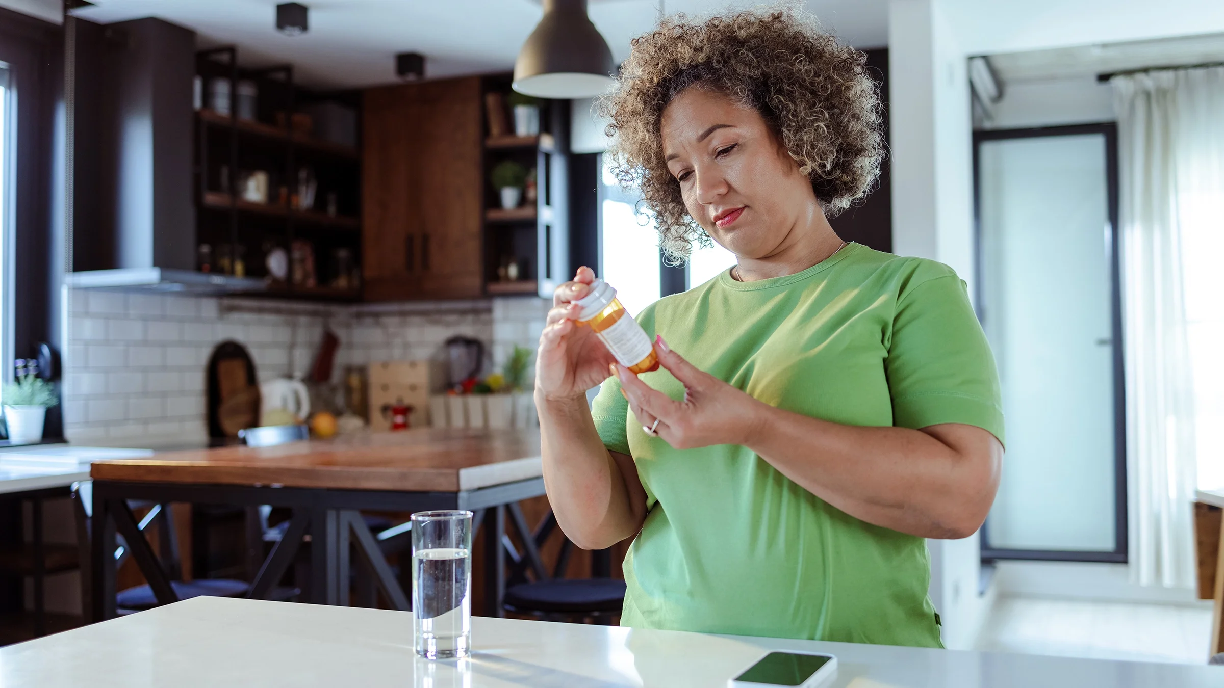 Woman reading Rx bottle at home in her kitchen