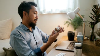 young man reading medication bottle 1311961863