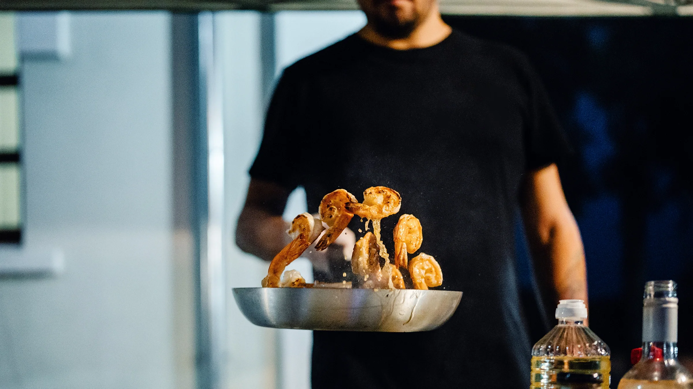 Chef cooking shrimp in a frying pan.