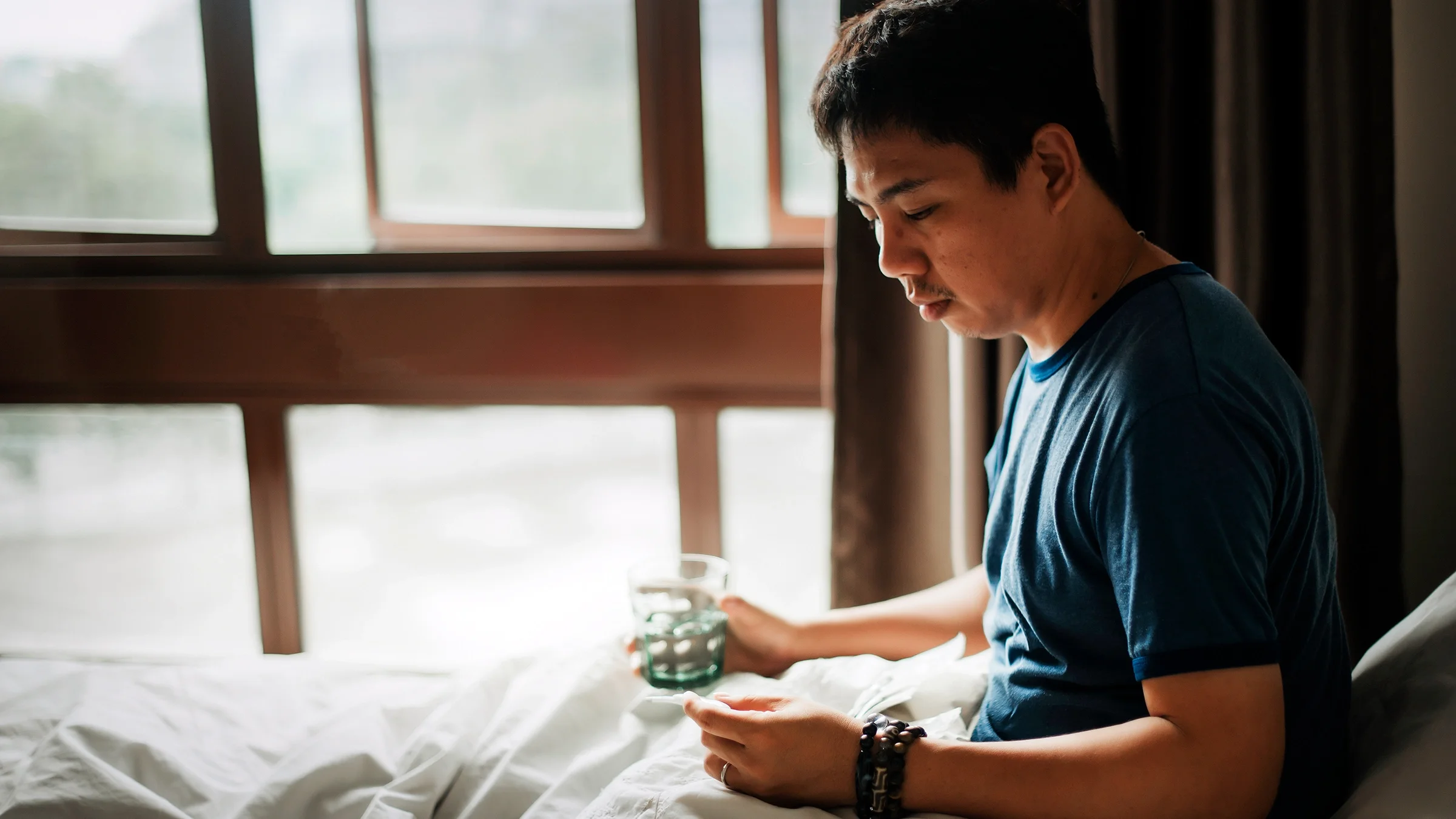 A man takes medication in bed.