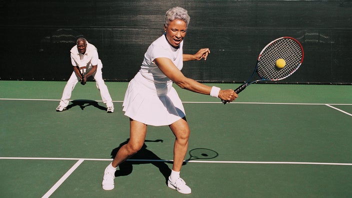A senior couple plays doubles tennis.