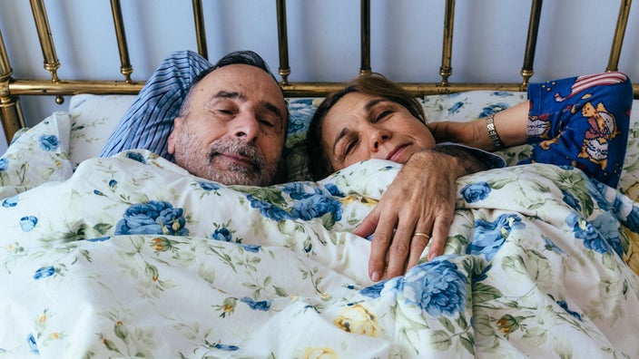 An older couple snuggling in bed.