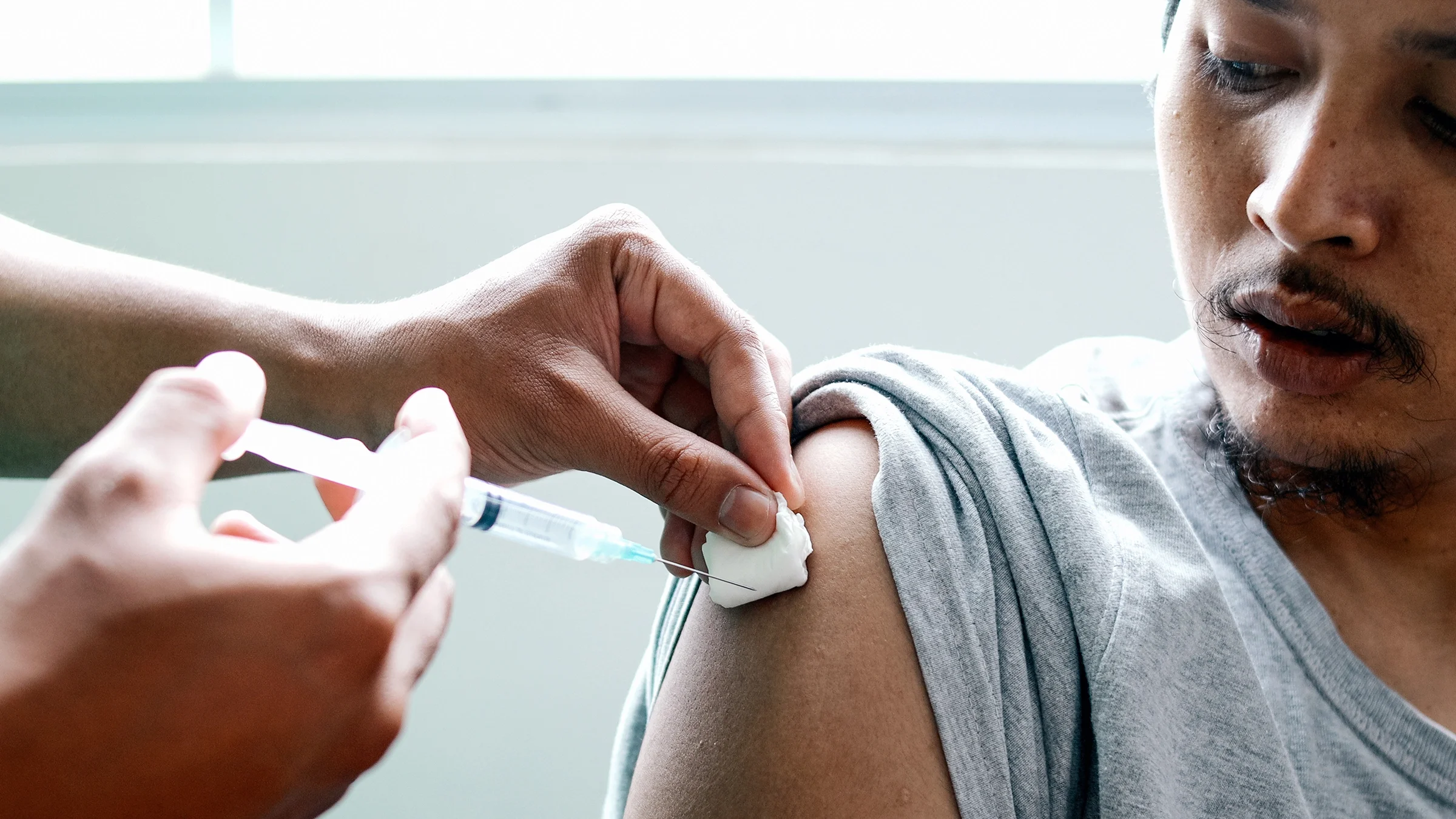 A close-up of a man receiving a vaccine in his arm.